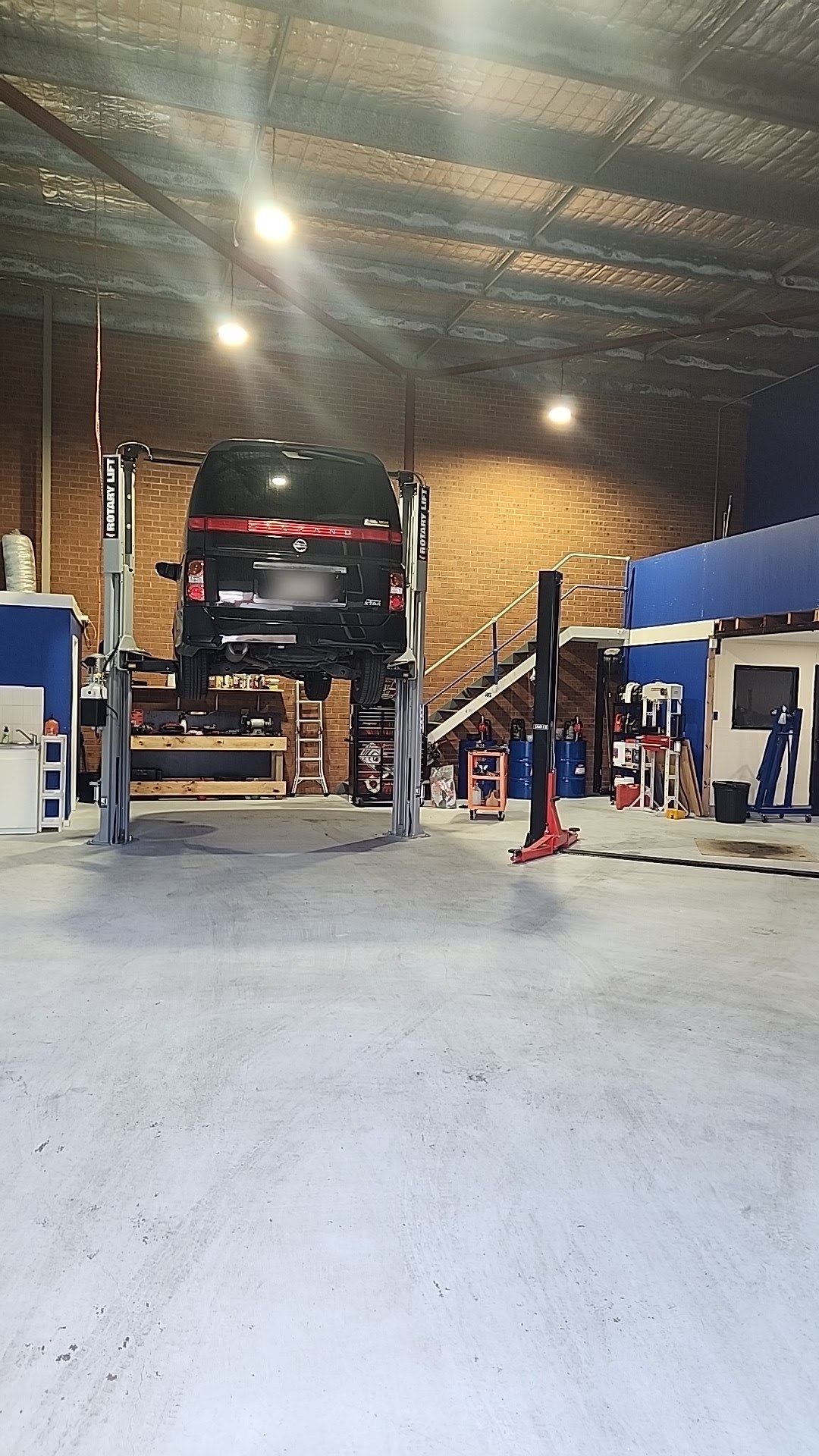 A people mover up on the two-post hoist inside the KR Auto Repair workshop
